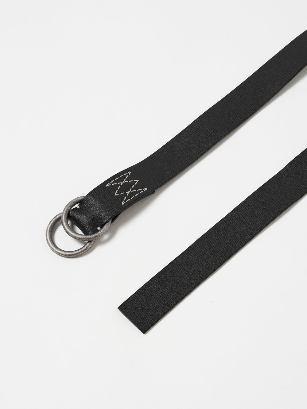 Close-up of a Black Leather O Ring Belt on a white surface. The belt features a silver O-ring and white stitching.