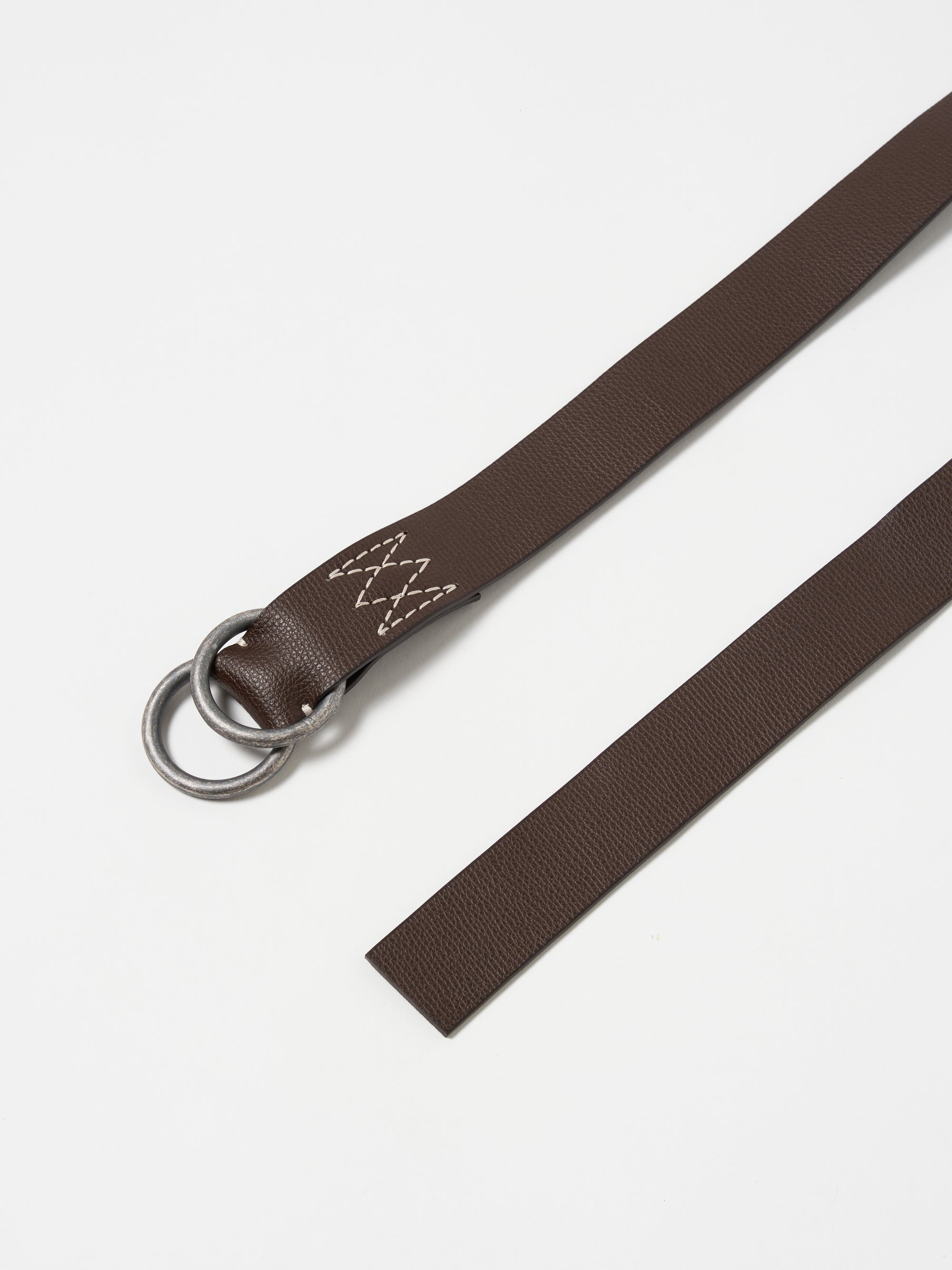 Close-up of a Brown Leather O Ring Belt on a white surface. The belt features a silver O-ring and visible stitching.