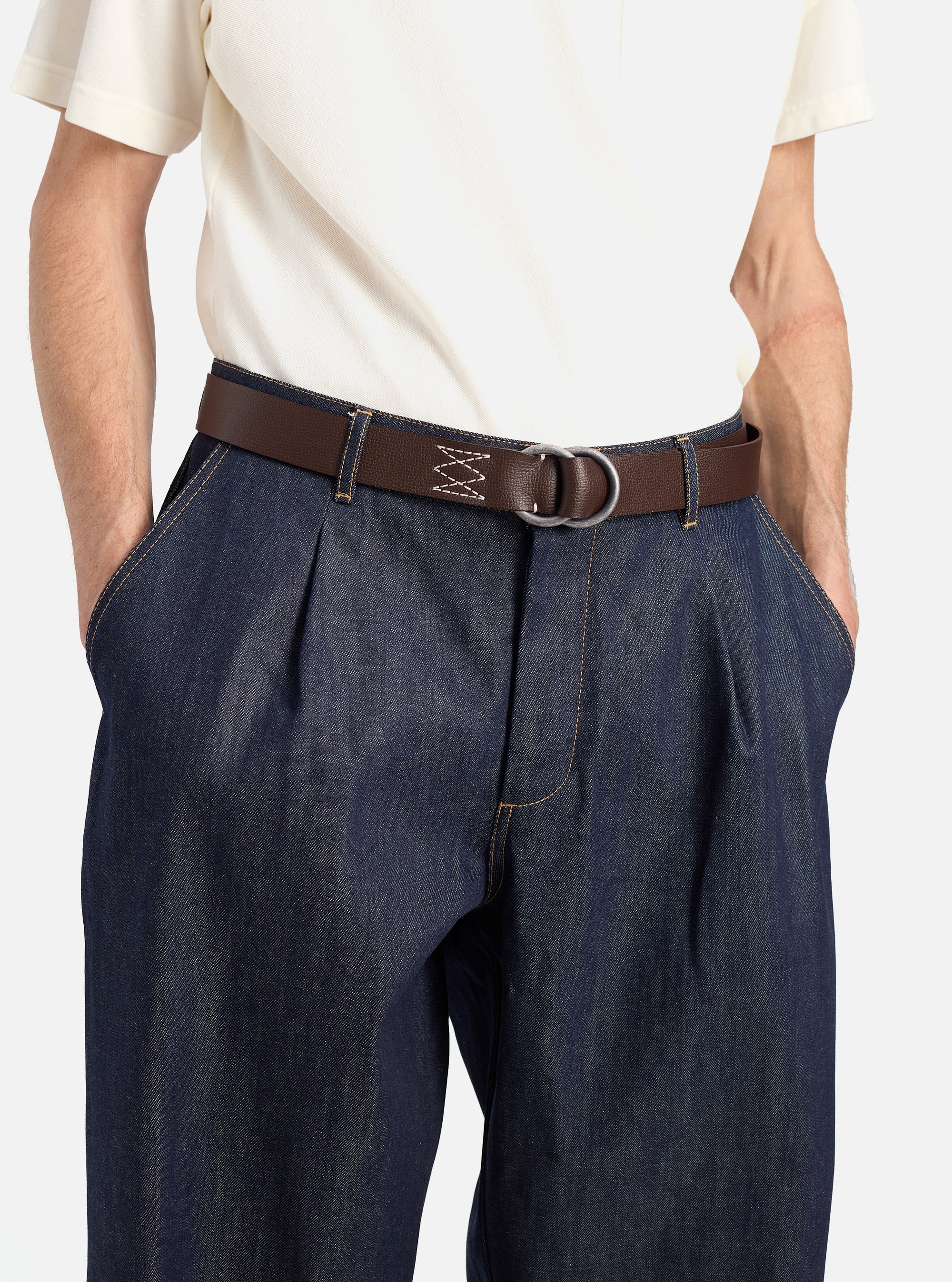 A model wears a Brown Leather O Ring Belt with dark denim pants and a cream shirt against a white background. The belt is brown leather with a silver O ring buckle.