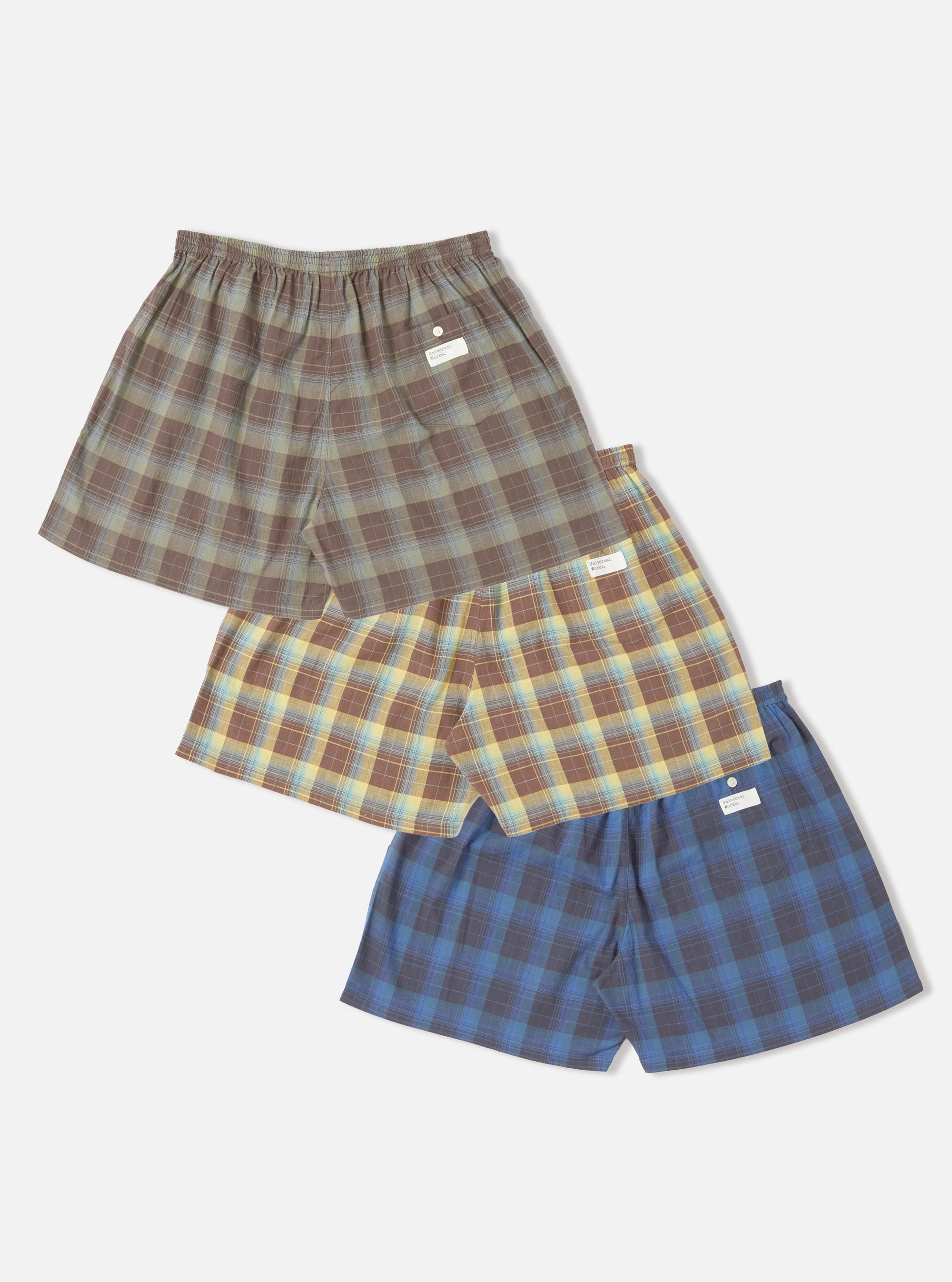 Stacked Multi Check 3 Pack Boxer Short on a white background. The boxers are brown, yellow, and blue plaid with an elastic waistband.