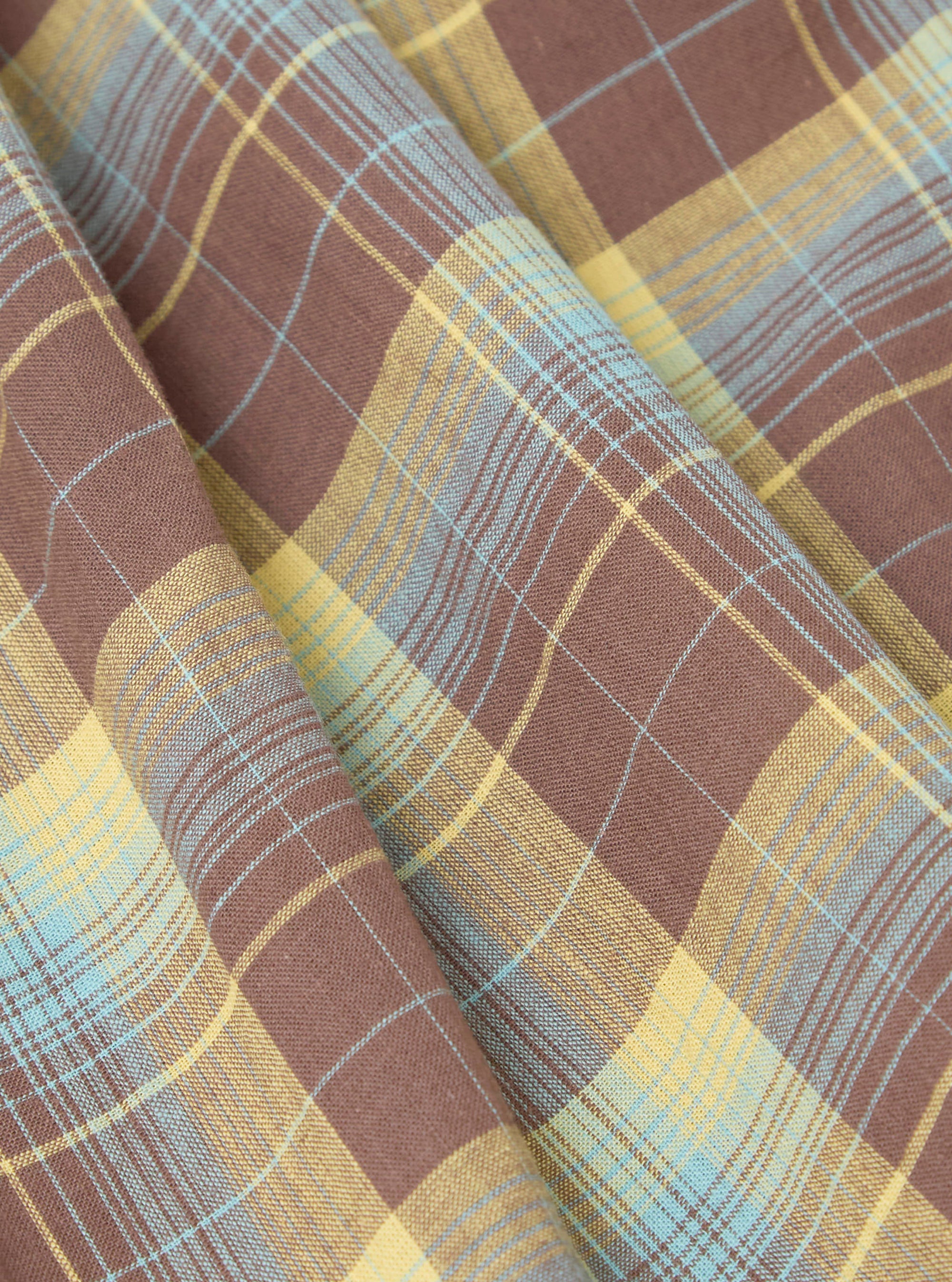 Close-up of Multi Check 3 Pack Boxer Short fabric. Brown, yellow, and blue plaid pattern. Soft cotton material, folded on a flat surface.