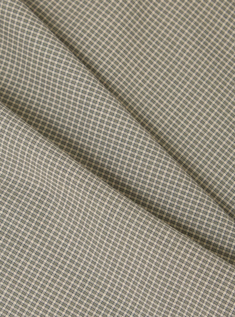 Close-up of the Green Tiny Check Boxer Short fabric. The material is a light beige with a small green check pattern. The fabric is folded on a plain surface.