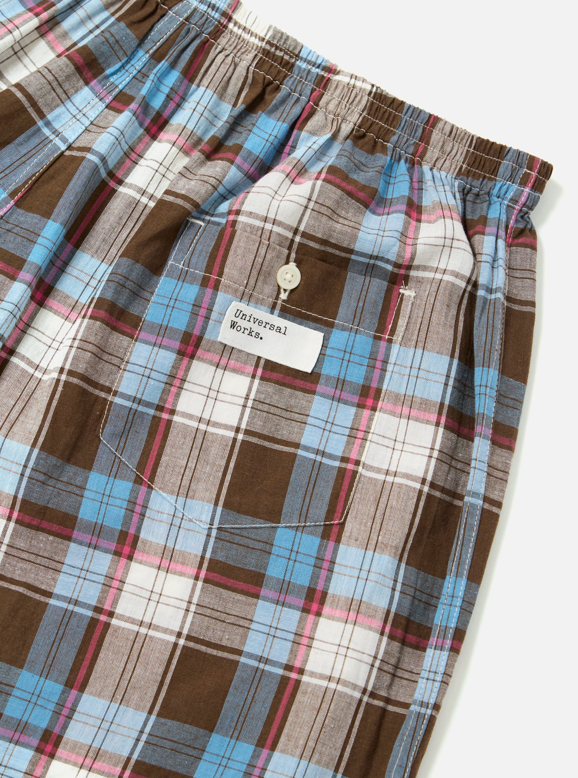 Close-up of the Blue/Brown Check 3 Boxer Short on a white surface. Features a brown, blue, pink, and white plaid pattern, elastic waistband, and a small pocket with a button.