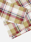 Close-up of the Red/Brown Kip Check Long Pyjama Set fabric. The cotton blend features a red, brown, and blue plaid pattern on a white background. Shot on a white surface.