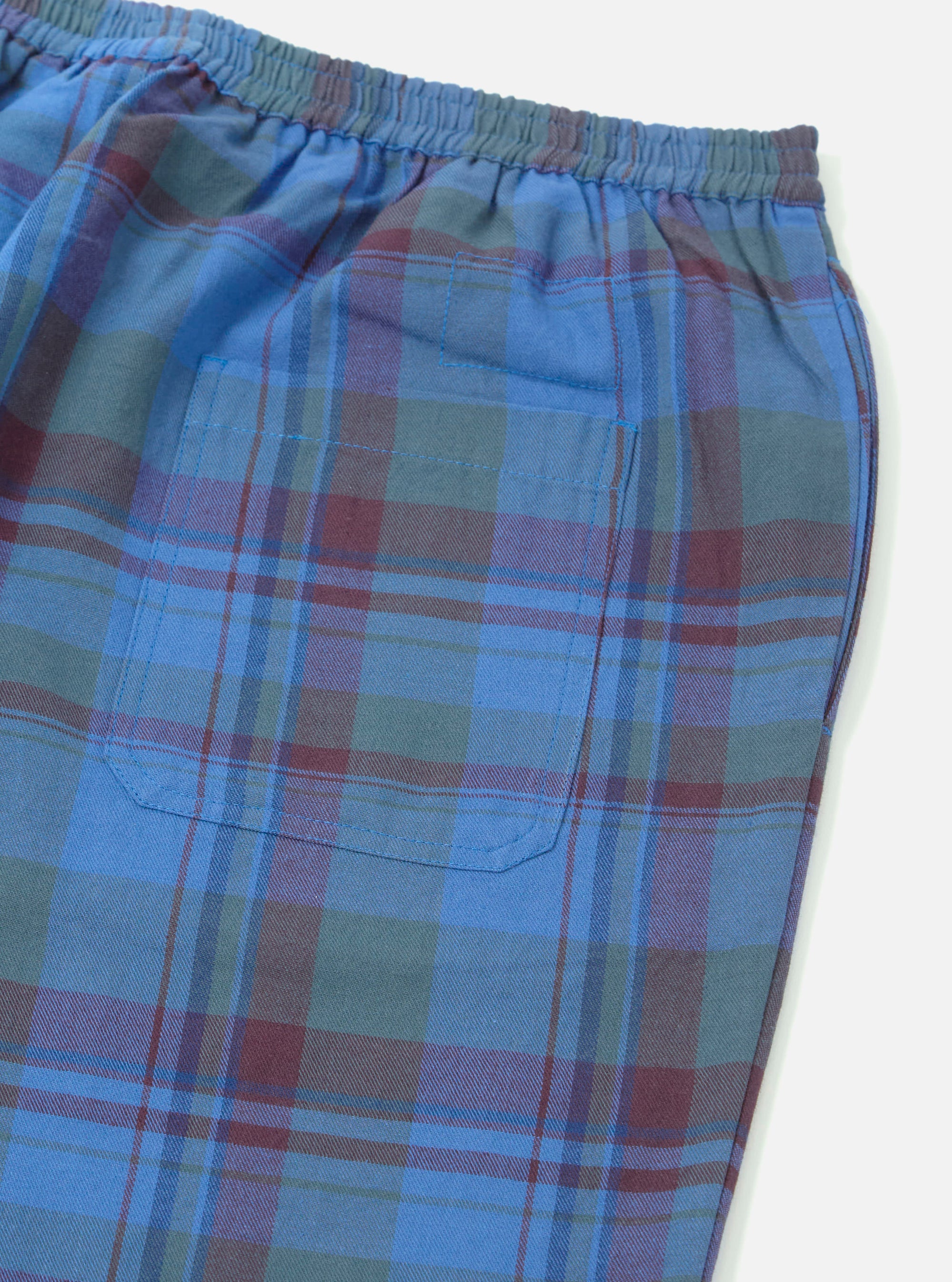 Close-up of the Blue Kip Check Long Pyjama Set bottoms, showing the blue, green, and maroon plaid pattern, elastic waistband, and pocket detail against a white background.