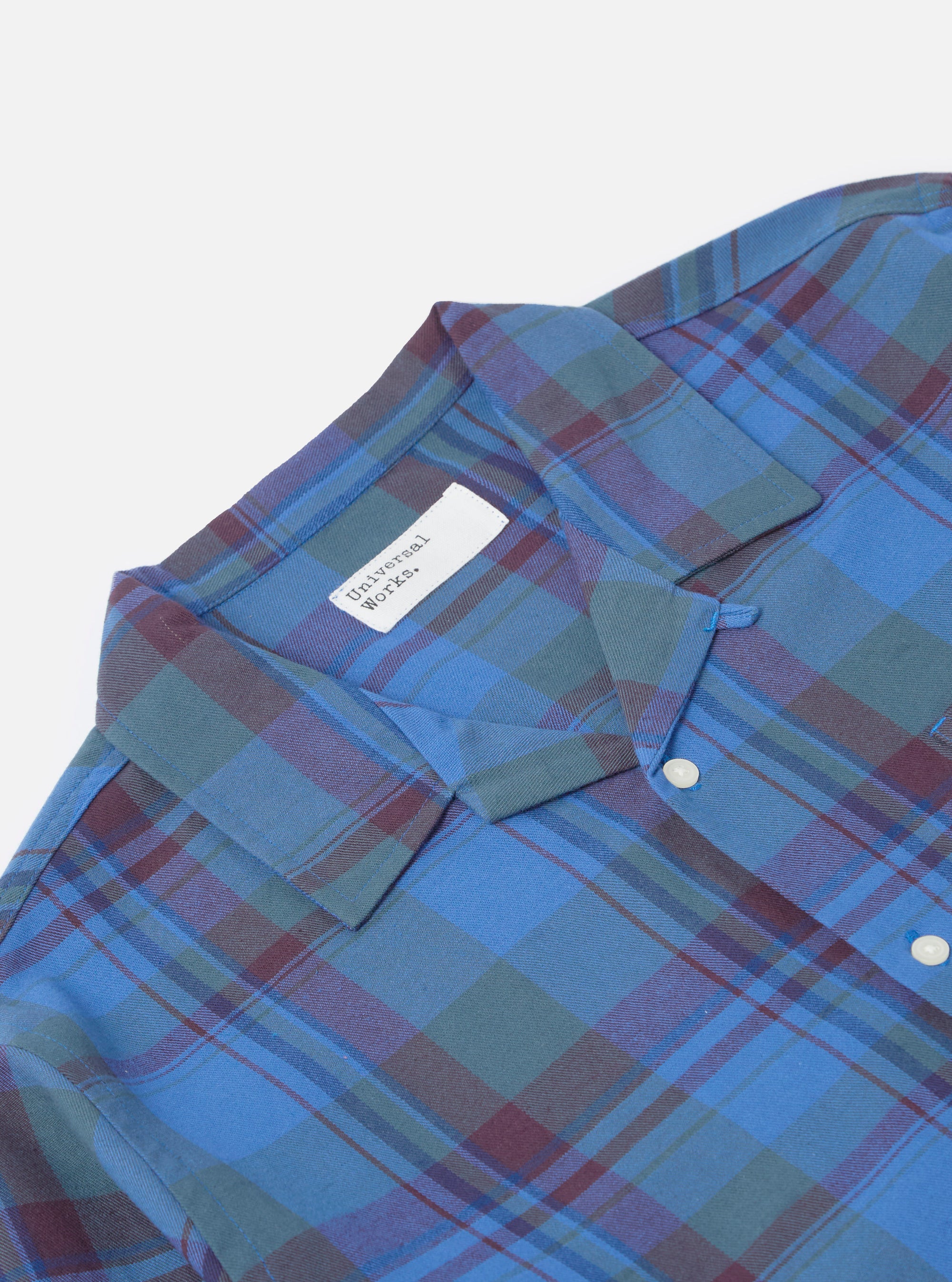 Close-up of the Blue Kip Check Long Pyjama Set top on a white background. The blue, green, and maroon plaid shirt has a collar and white buttons.
