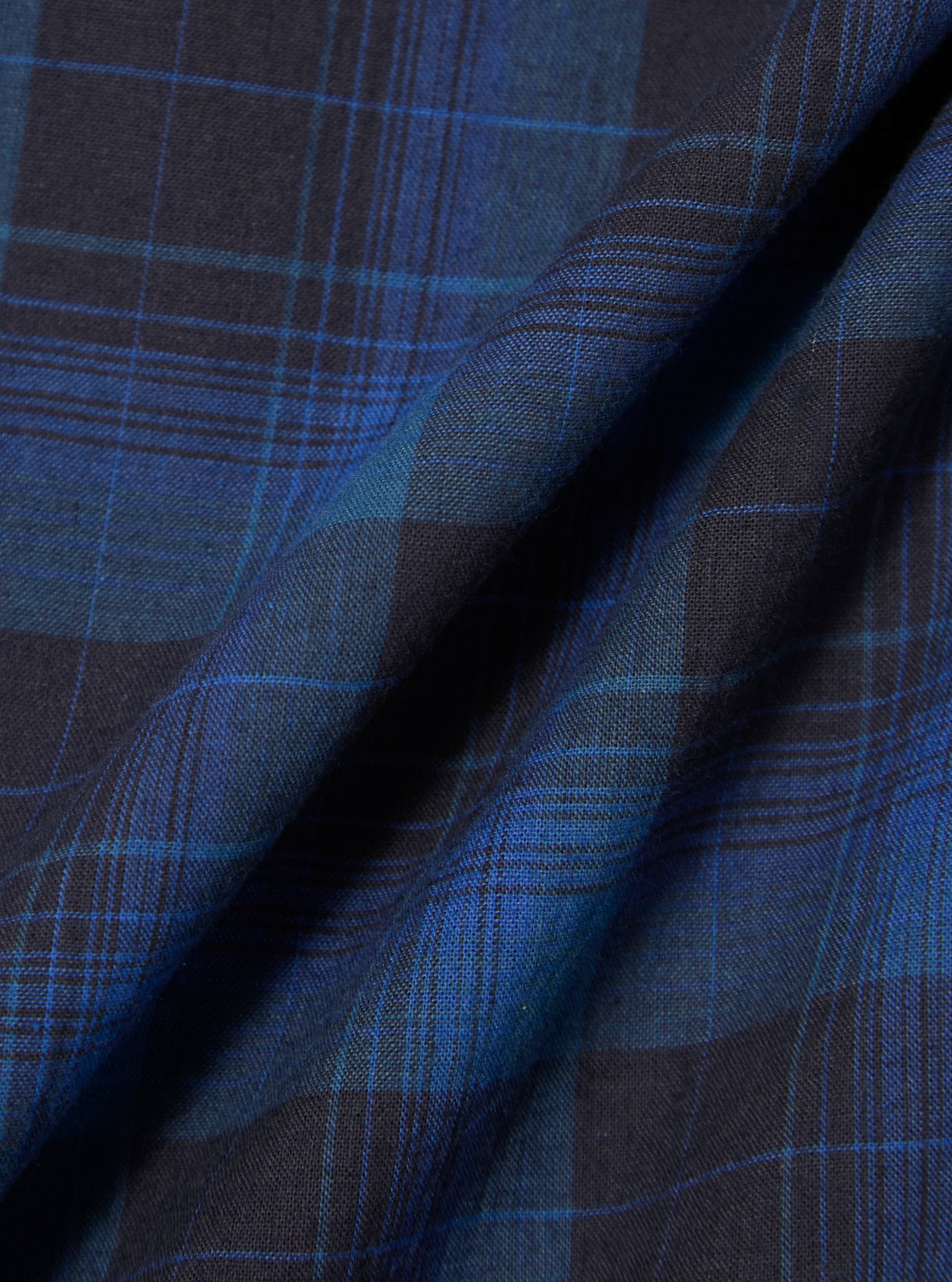 Close-up of the Navy/Blue Check Long Pyjama Set fabric. The material is folded, showing the navy and blue check pattern. The background is plain.