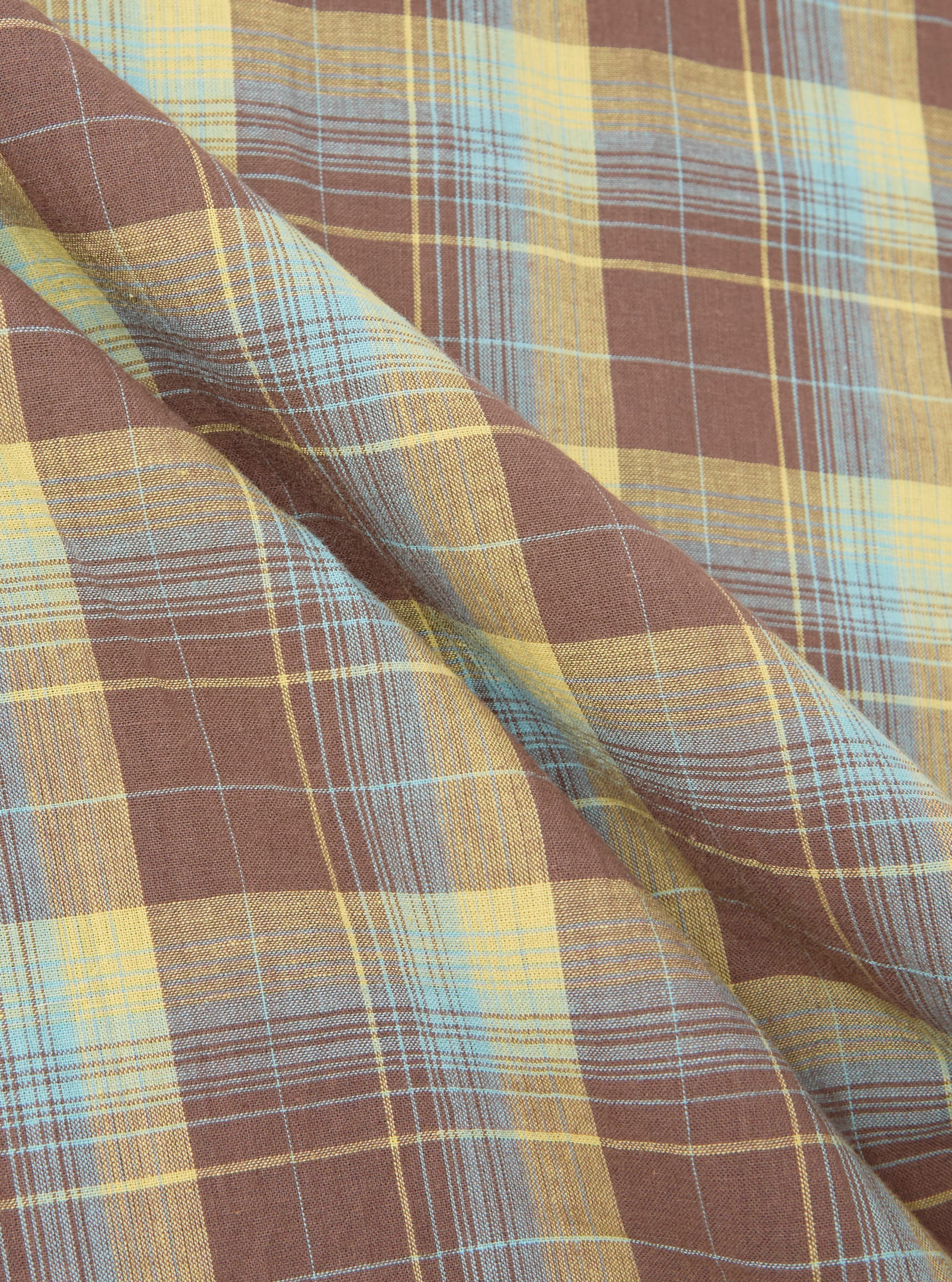 Close-up of the Yellow/Brown Check Short Pyjama Set fabric. The soft, brushed cotton features a yellow, brown, and blue plaid pattern with gentle folds.