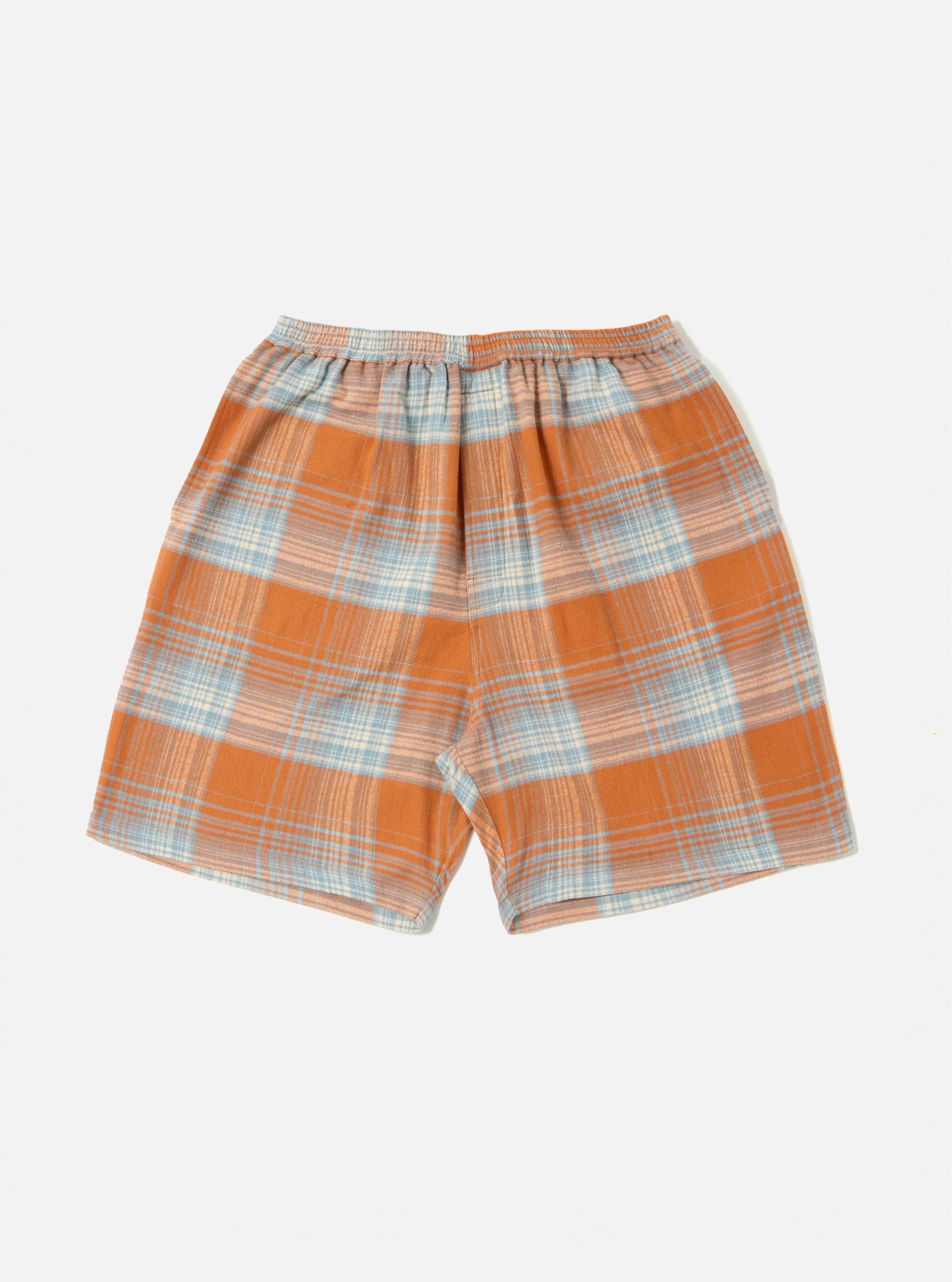 The Orange Check Pyjama Short, featuring a orange and blue plaid pattern, laid flat on a white background. The shorts have an elastic waistband.