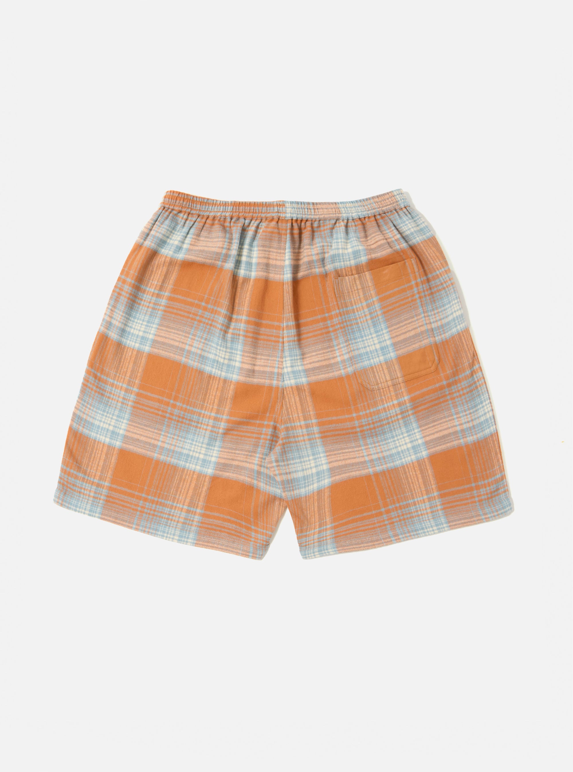 The Orange Check Pyjama Short, featuring an orange and blue plaid pattern, is laid flat on a white background. The shorts have an elastic waistband and a back pocket.