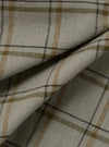 Close-up of the Green PJ Plaid Pyjama Short fabric. The material is a light, neutral tone with green, brown, and black plaid lines. The fabric is folded.
