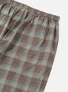 Close-up of the Green/Brown Check Pyjama Pant on a white surface. The fabric shows a plaid pattern with brown, green, and light blue lines. Elastic waistband and pocket detail visible.