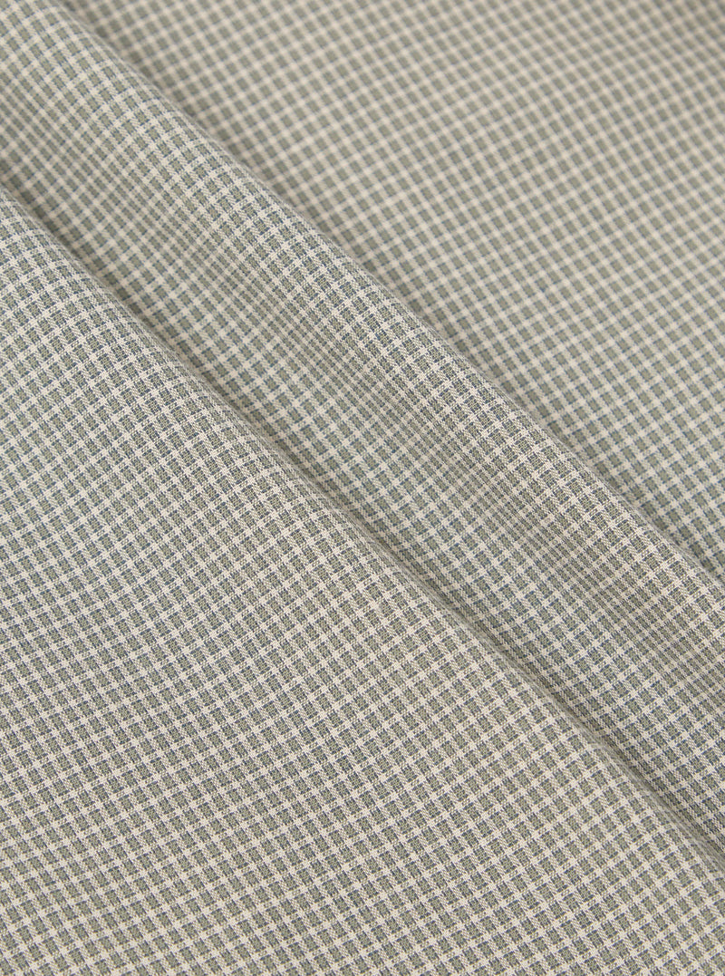 Close-up of the Green Tiny Check Pyjama Pant fabric. The material is a soft green and white tiny check pattern. The fabric is folded on a flat surface.
