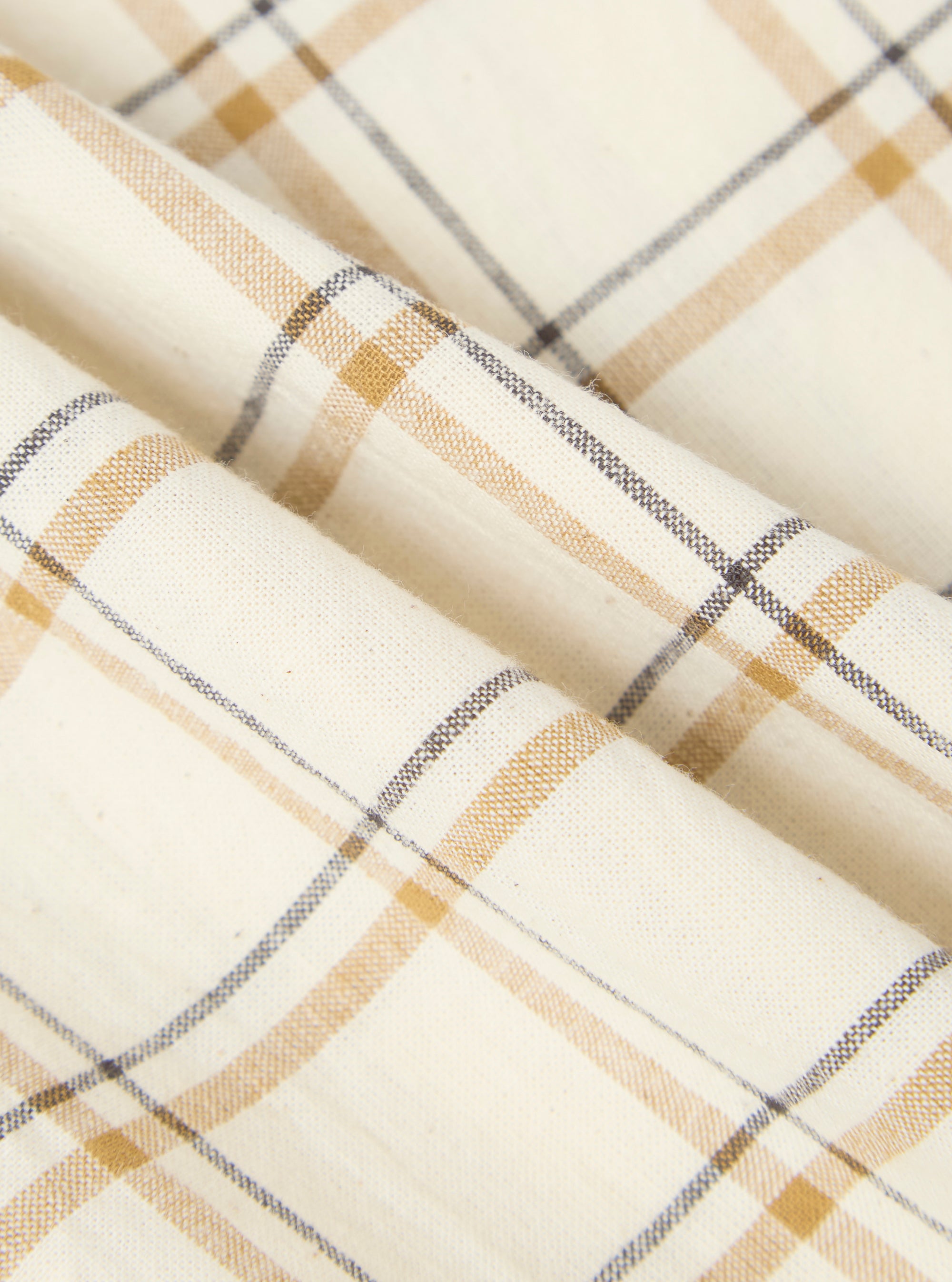 Close-up of the Ecru PJ Plaid Pyjama Pant fabric. The material is ecru with a plaid pattern in brown and gray. The fabric is folded, showing its texture.