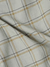 Close-up of the Green PJ Plaid Pyjama Pant fabric. The material is a soft, woven plaid with green, gold, and gray lines on a white background. The fabric is draped on a flat surface.