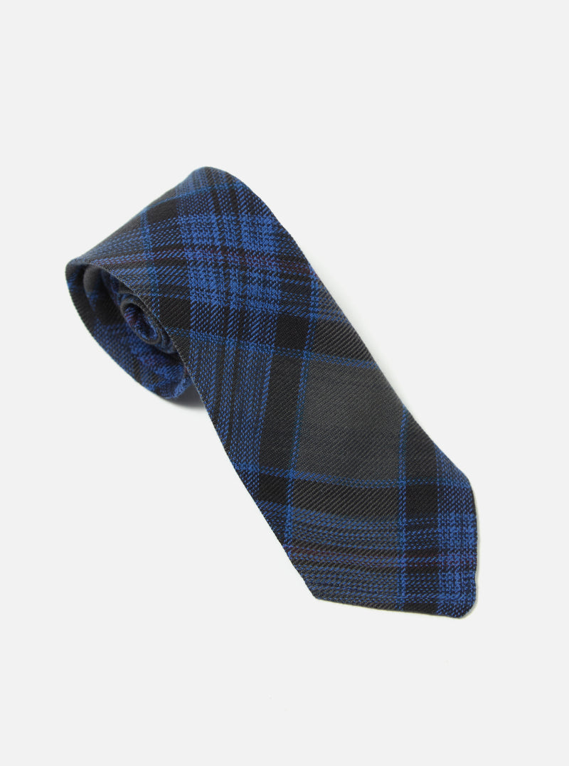 The Navy Ikat Twill Check Tie on a white surface. The tie has a blue and gray plaid pattern. The twill material gives it a textured look.