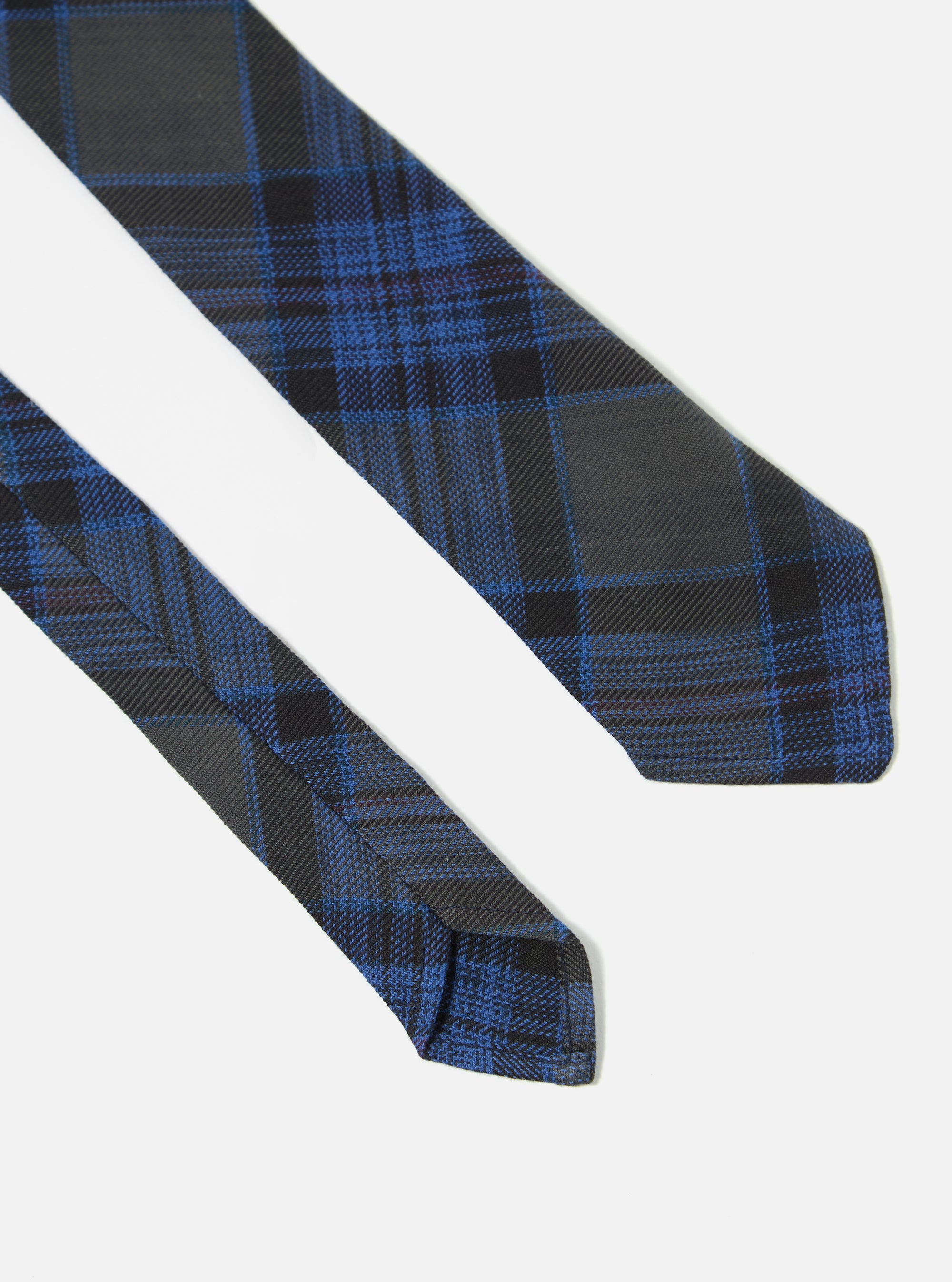 Close-up of a Navy Ikat Twill Check Tie on a white background. The tie features a blue and black check pattern.