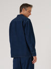 A man in an Indigo Work Denim Fatigue Shirt stands against a white background. The shirt is dark blue denim, long-sleeved, and buttoned. The fit is relaxed.