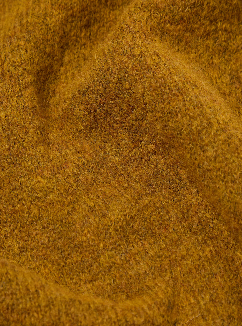 Close-up of the Gold Alpaca Knit Lyon Crew, showcasing the texture and color. The alpaca knit is soft and luxurious. The background is a simple, neutral surface.