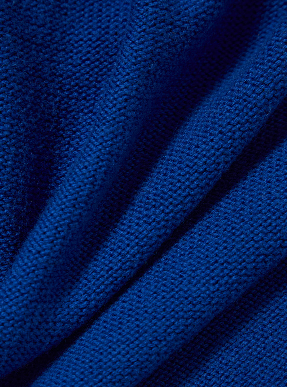 Close-up of the Work Blue Shetland Wild Seamless Crew sweater showing the texture of the knit. The bright blue wool is folded on a plain background.