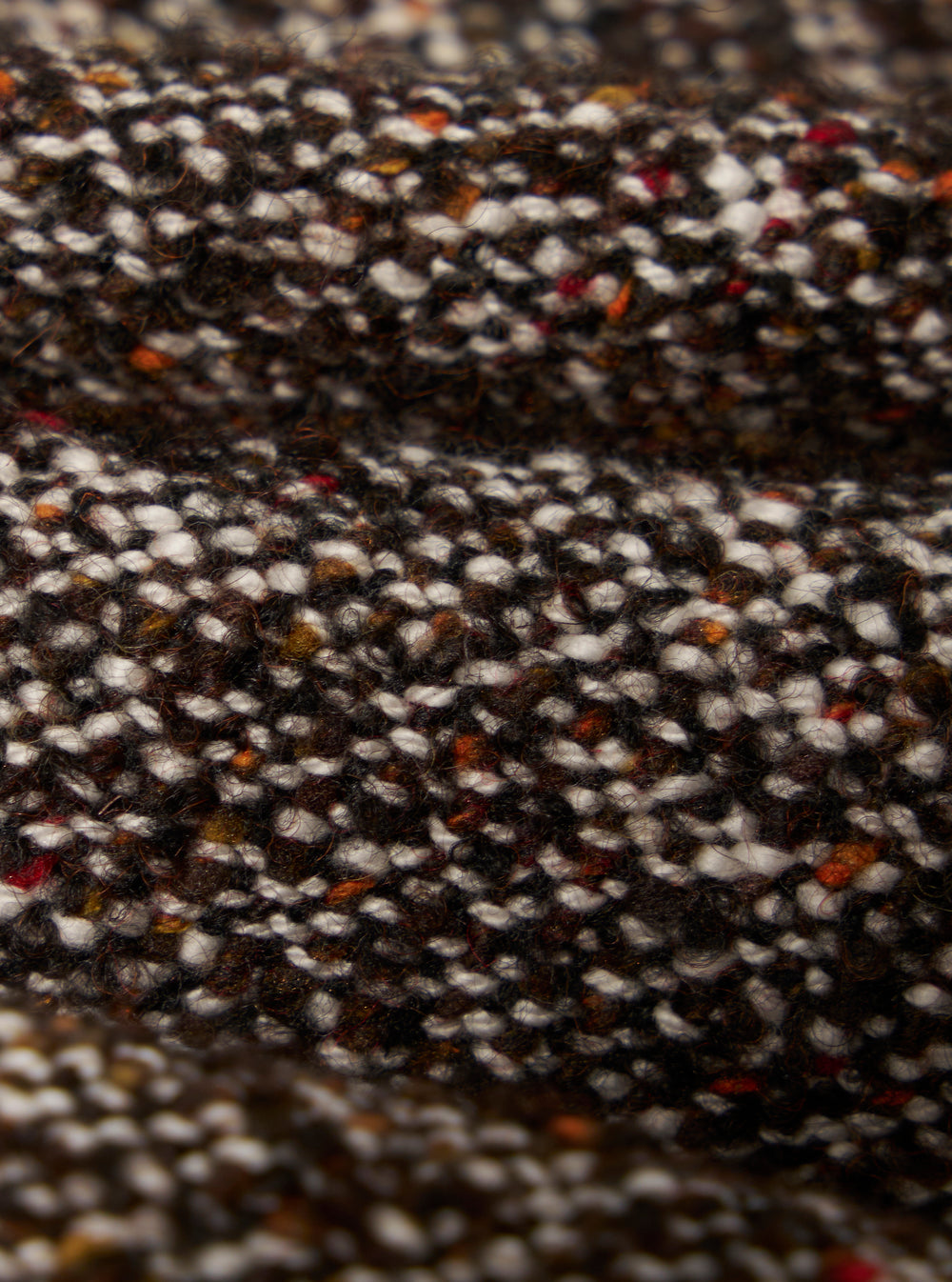 Close-up of the Brown Sedona Tweed Zip Shirt fabric. The tweed is a mix of brown, white, and orange fibers, creating a textured look.