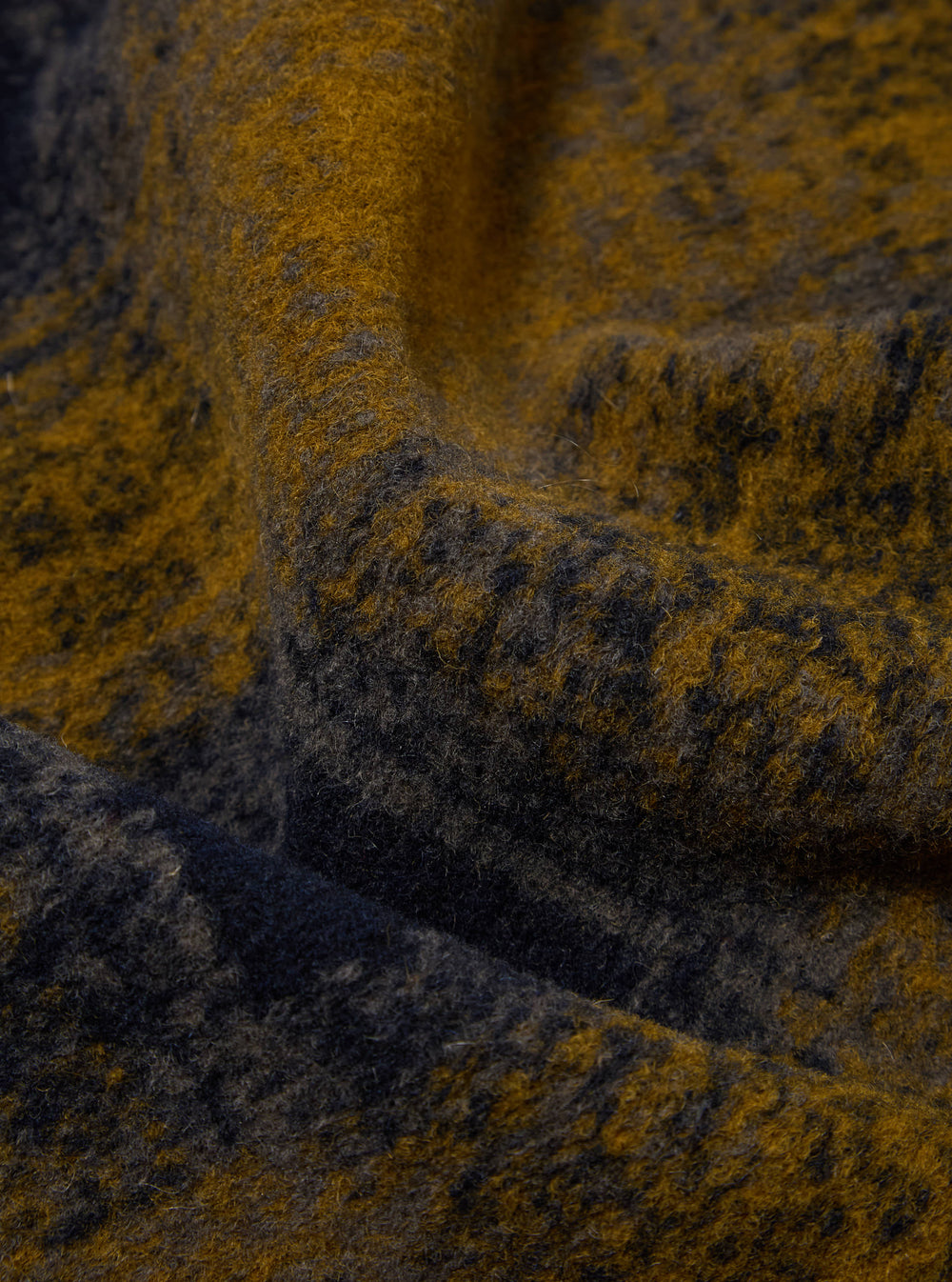Close-up of the Navy Check Techno Melton Check Field Jacket fabric. The material is a textured blend of navy and gold yarns, creating a subtle check pattern.
