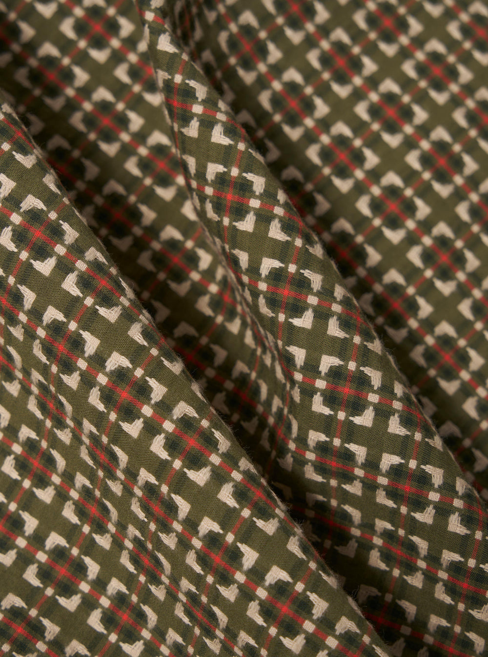 Close-up of the Olive Oscar Cotton Zip Shirt fabric. The material is olive green with a red and white pattern. The shirt is displayed on a flat surface.