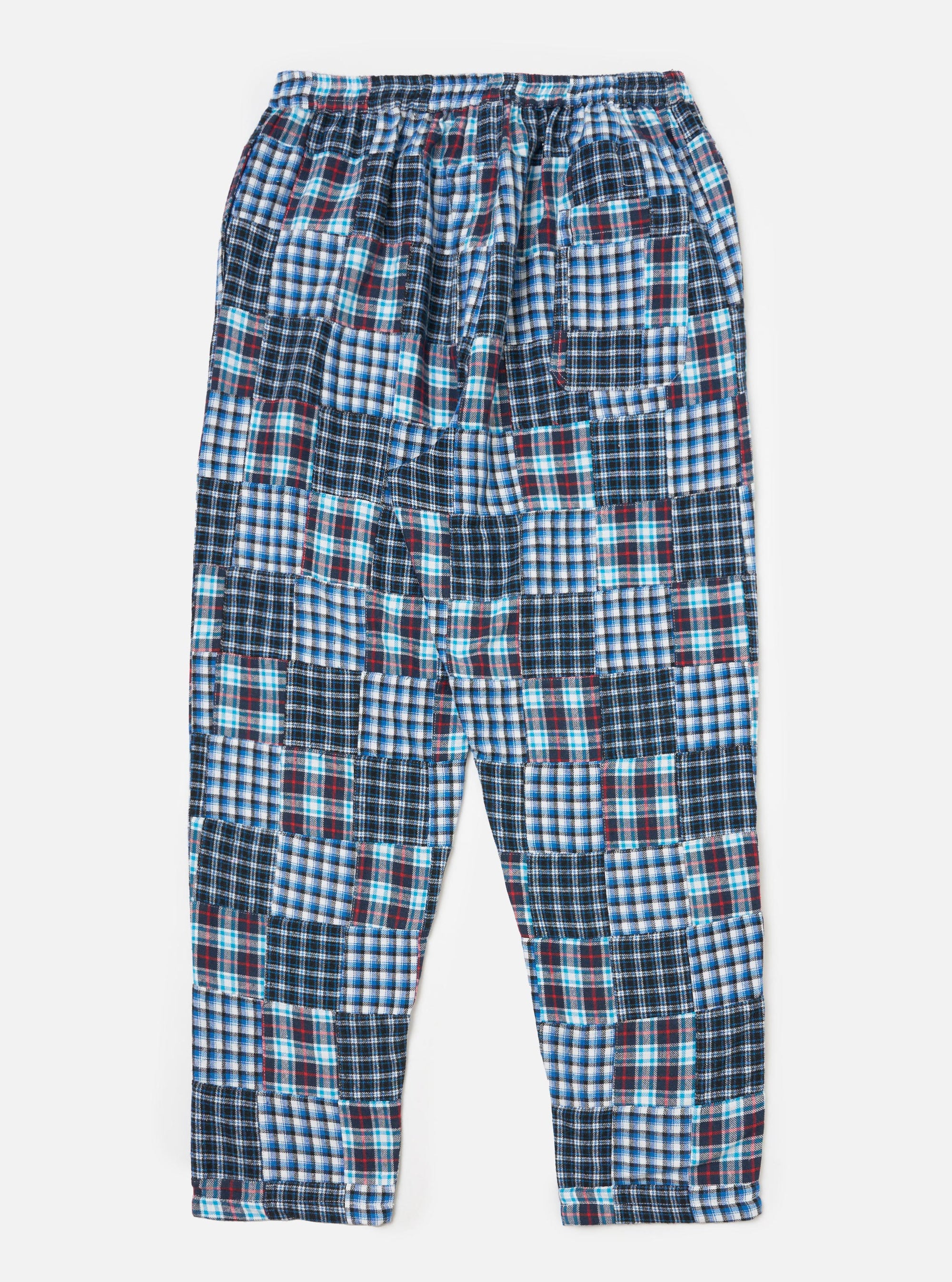 The blue brushed patchwork pyjama pant is laid flat on a white background. The pant has a patchwork design with blue, white, and red plaid patterns.