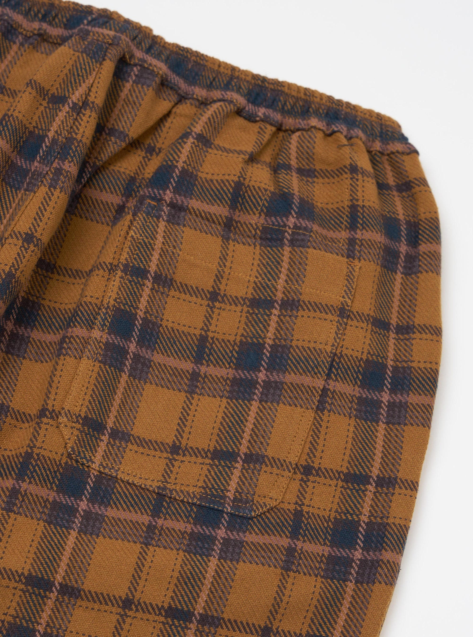 Close-up of the Caramel Twill Check Pyjama Pant on a white background. The caramel, navy, and mauve check pattern is visible, along with the elastic waistband and pocket.