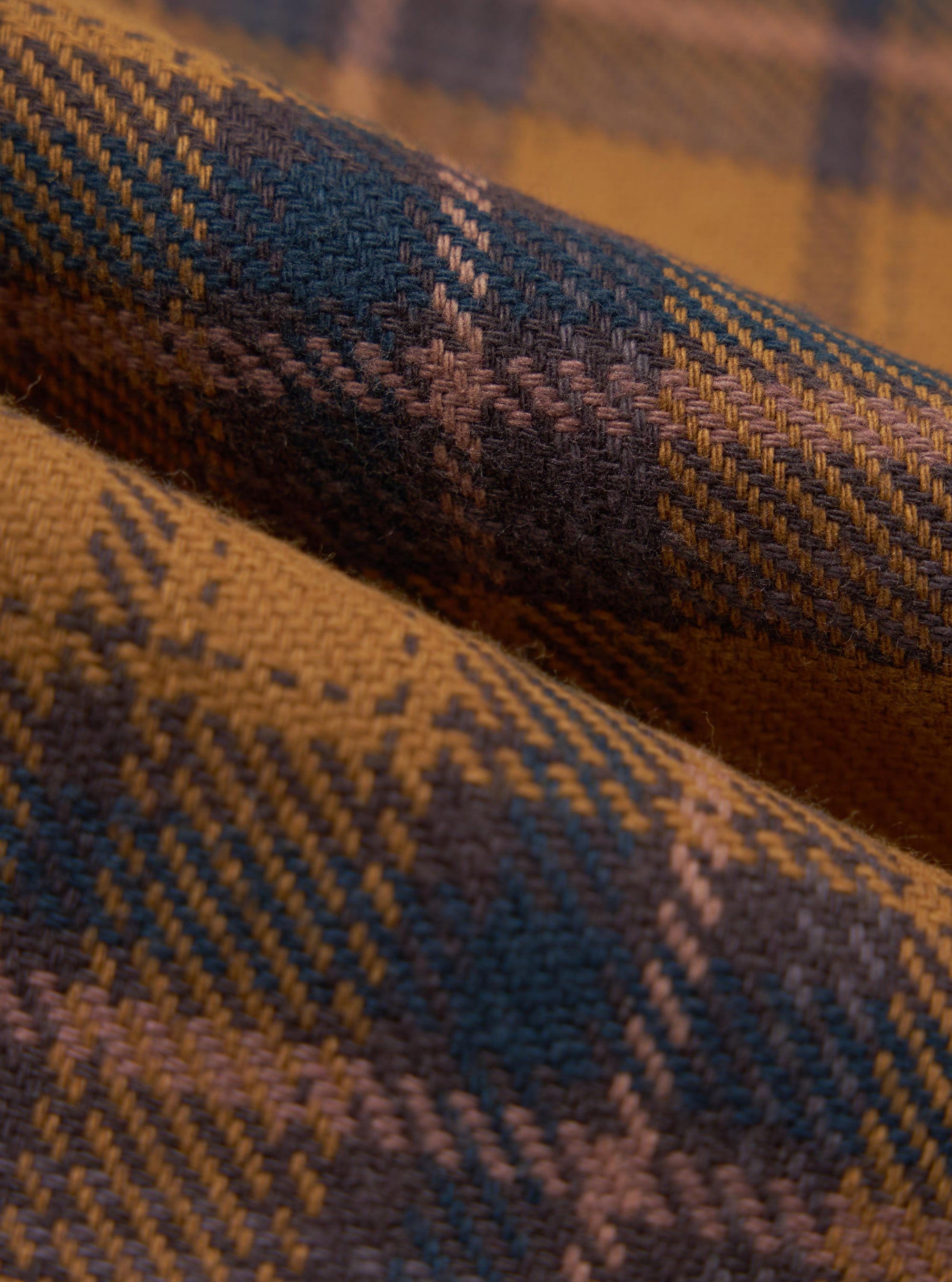 Close-up of the Caramel Twill Check Pyjama Pant fabric. The caramel, brown, and blue twill weave creates a soft, cozy texture. Perfect for relaxed evenings.