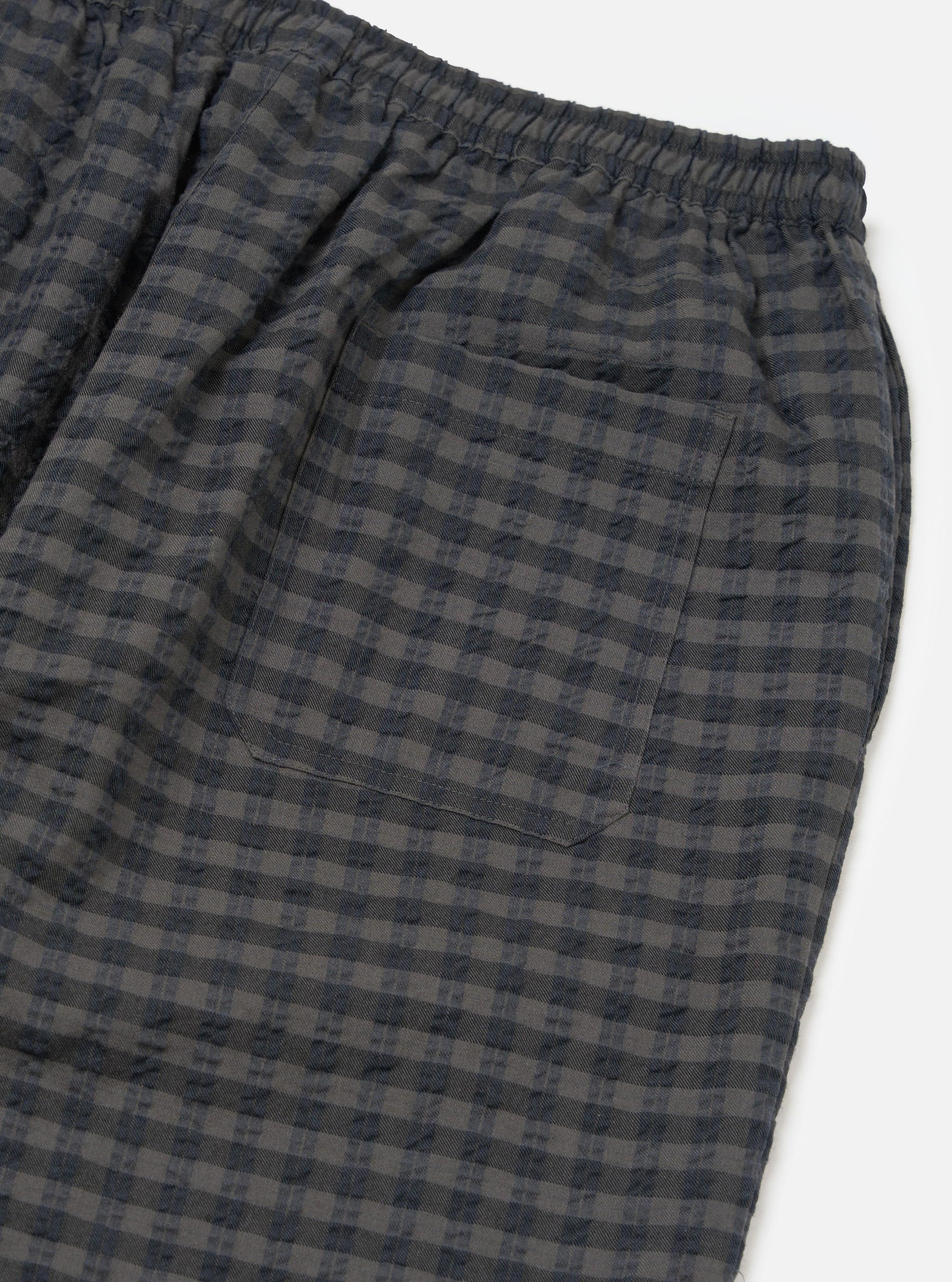 Close-up of the Charcoal/Navy Seersucker Plaid Pyjama Pant on a white background. Shows the elastic waist and back pocket. The fabric is a textured plaid.