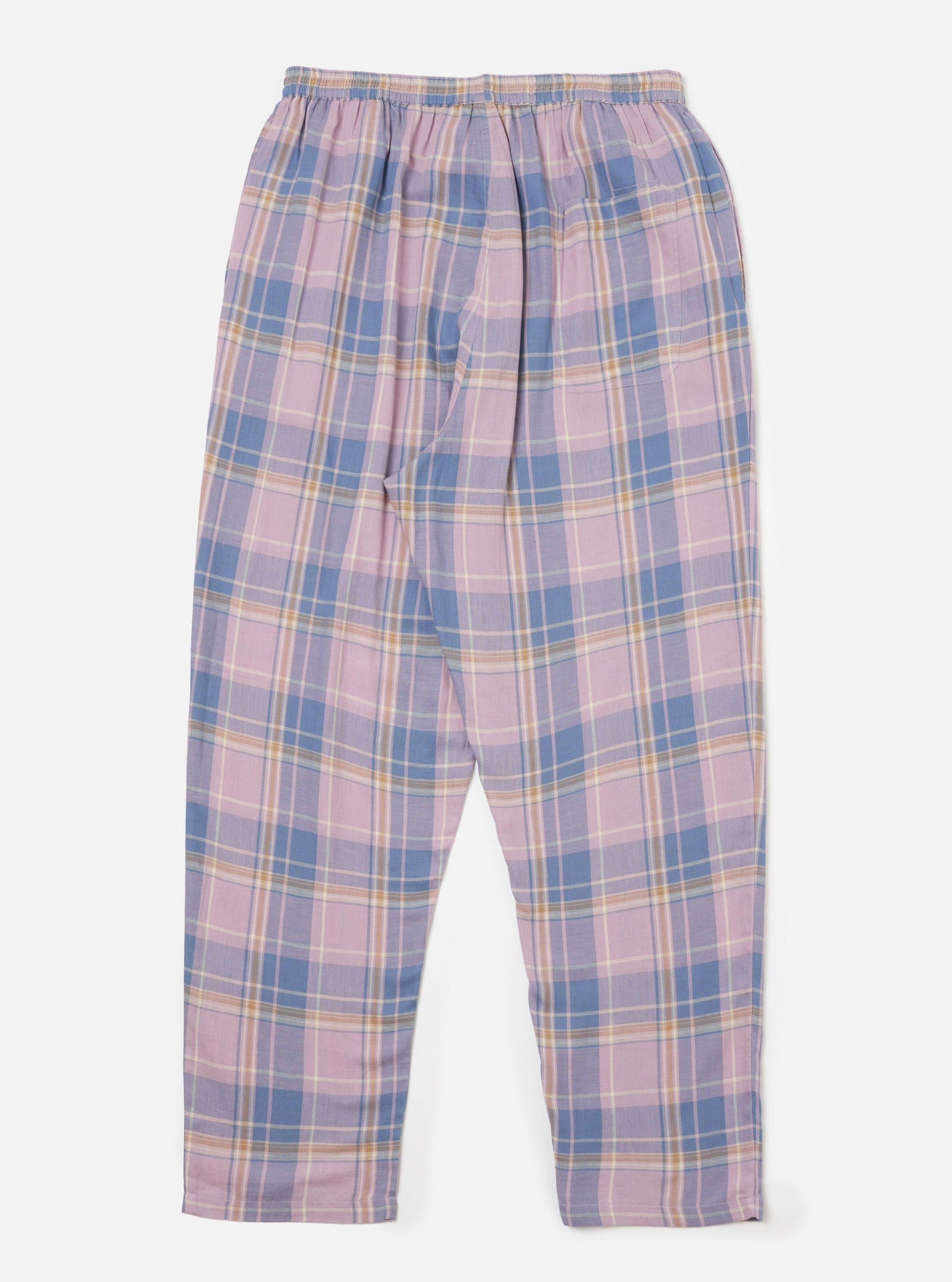 The Pink/Blue Pastel Plaid Pyjama Pant is laid flat on a white background. The pants have an elastic waist and a relaxed fit. The plaid pattern features pink, blue, and cream colors.