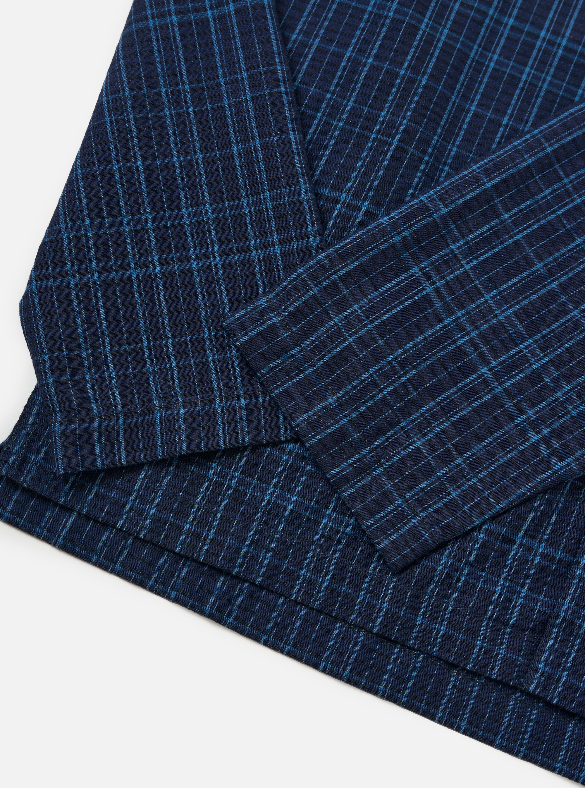 Close-up of the Indigo Plaid Long Pyjama Set. The fabric is a dark blue plaid with lighter blue accents, laid on a white surface.
