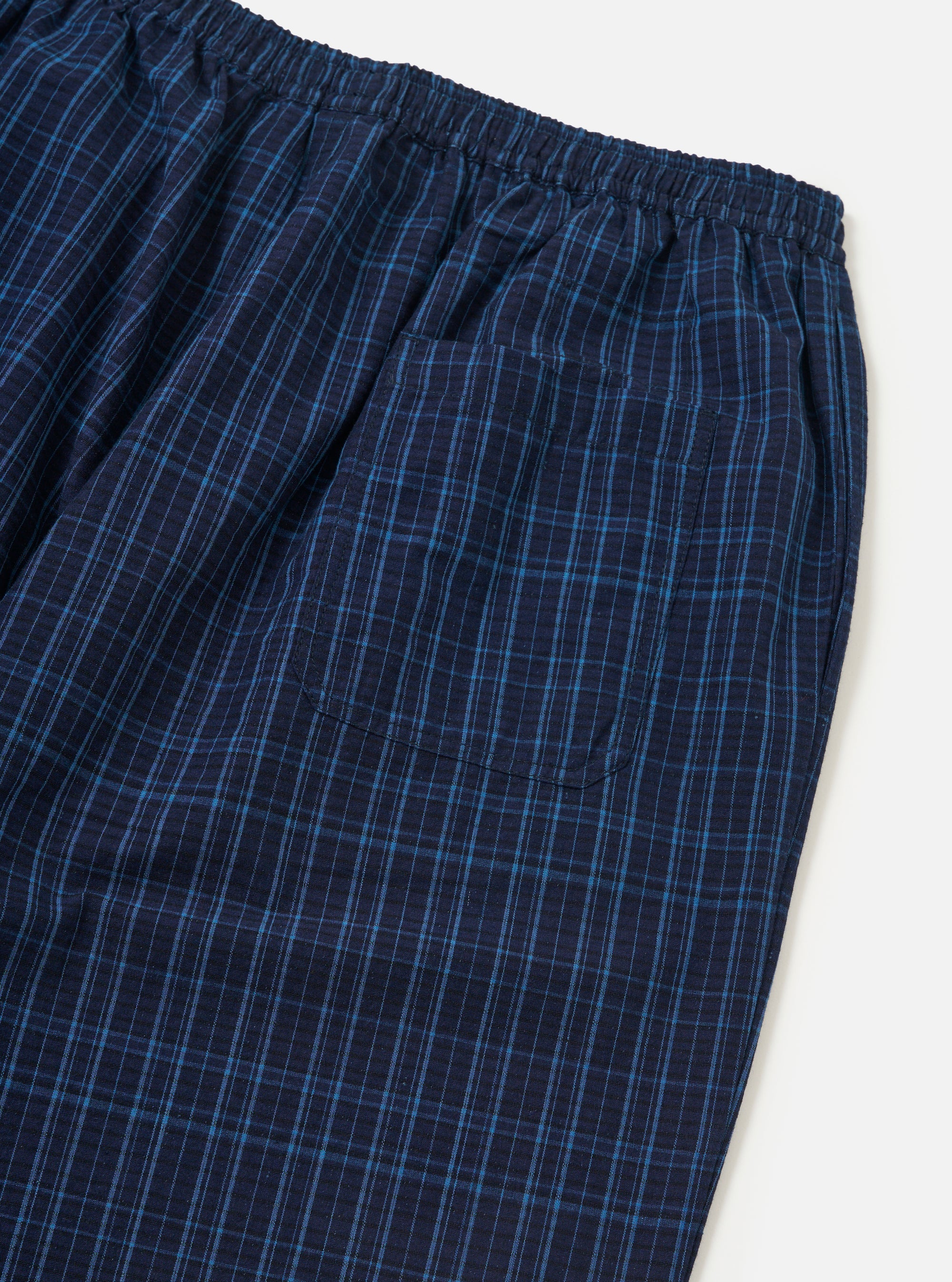 Close-up of the Indigo Plaid Long Pyjama Set. The blue plaid cotton pants have an elastic waist and a pocket. Shot on a white background.