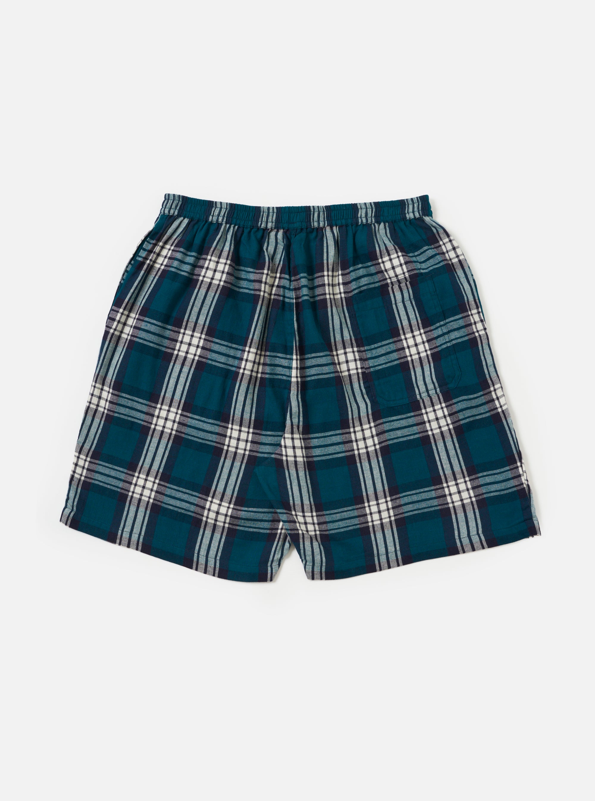 The Forest Brushed Plaid Pyjama Short, featuring a teal, navy, and white plaid pattern, elastic waist, and relaxed fit, is laid on a white surface.