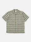 Close-up of the Green Busy Plaid Short Pyjama Set top, laid flat on a white background. The shirt is a green, cream, and black plaid with short sleeves and a button-down front.