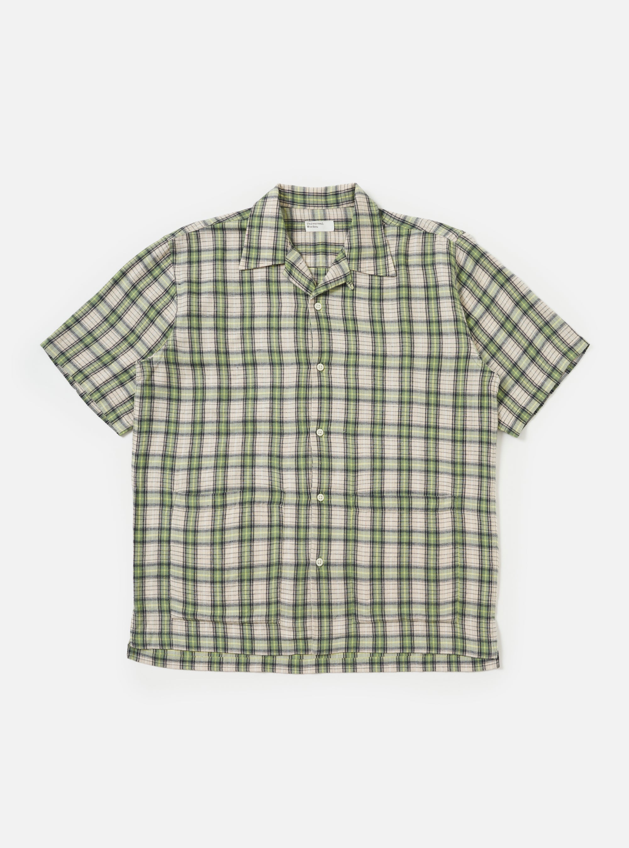 Close-up of the Green Busy Plaid Short Pyjama Set top, laid flat on a white background. The shirt is a green, cream, and black plaid with short sleeves and a button-down front.