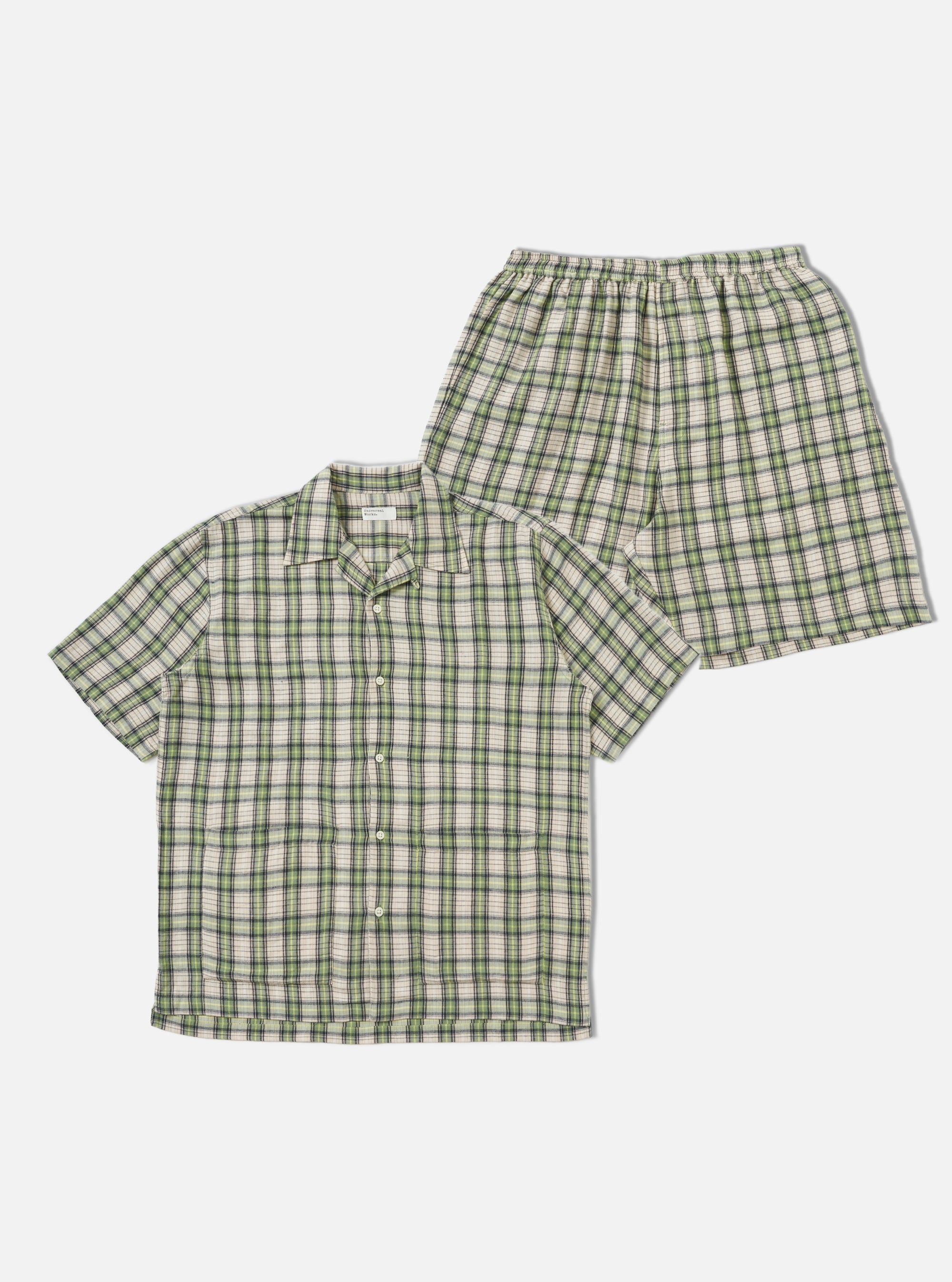 The Green Busy Plaid Short Pyjama Set, featuring a button-down shirt and elastic-waist shorts in a green, beige, and black plaid pattern, staged on a white background.
