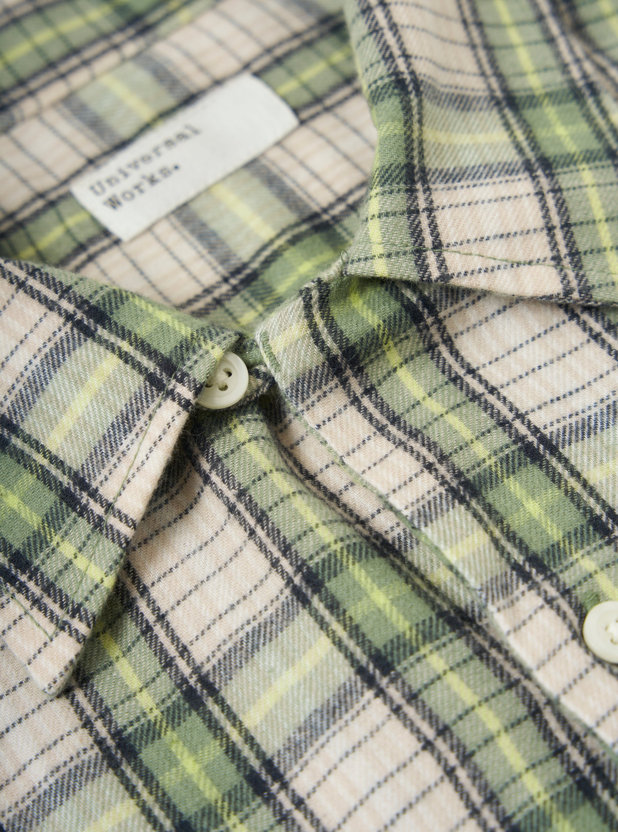 Close-up of the Green Busy Plaid Short Pyjama Set shirt, showcasing the green, beige, and black plaid pattern, button details, and brand label.