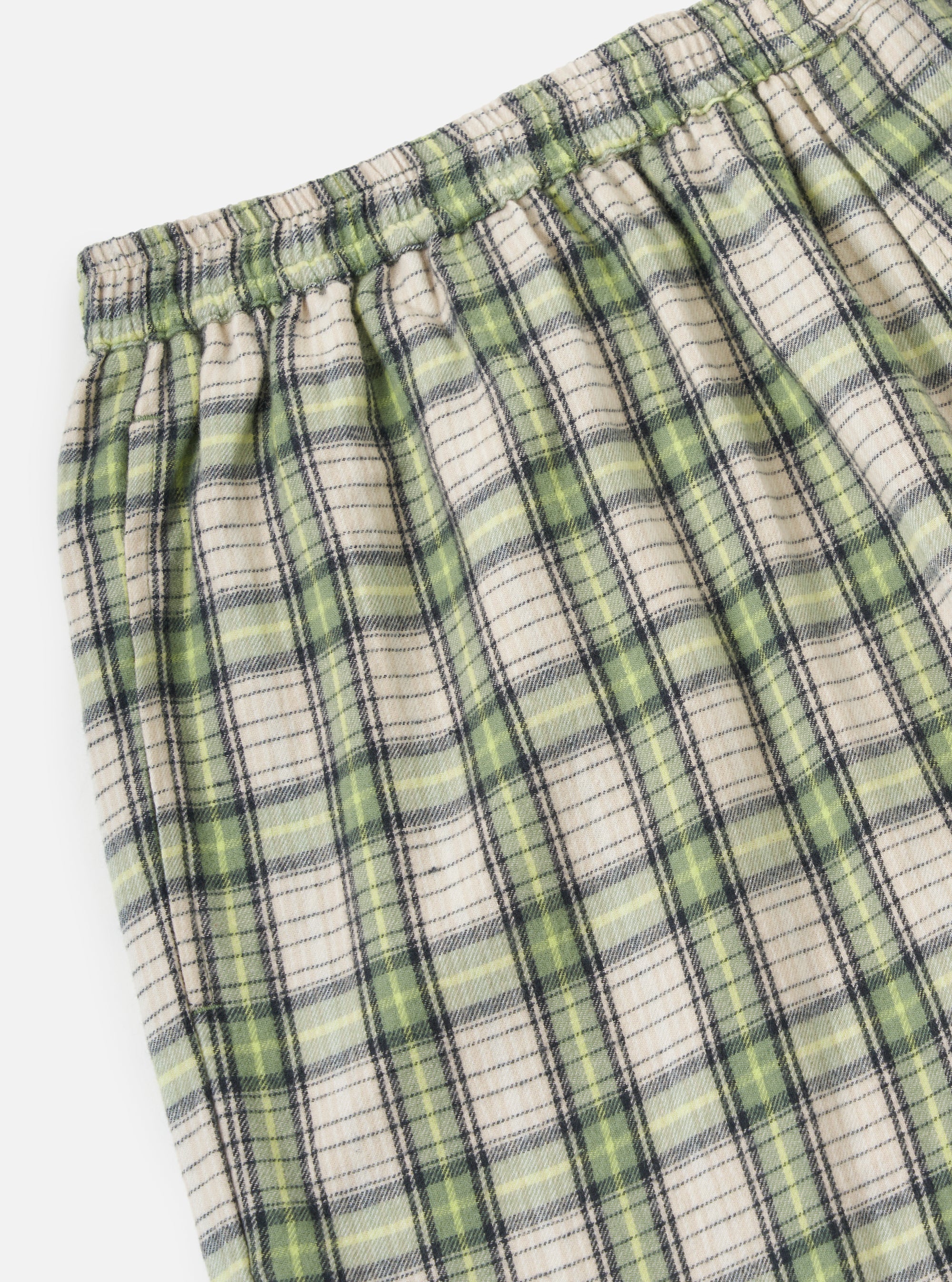 Close-up of the Green Busy Plaid Short Pyjama Set. The fabric is a soft plaid with green, beige, and black lines. The background is a plain white.