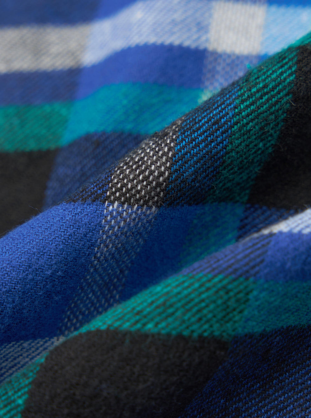 Close-up of the Blue Night Check Short Pyjama Set fabric. Features a blue, green, black and white check pattern. The material is folded and textured.