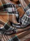 Close-up of the Brown Ikat Twill Check Long Pyjama Set fabric. The twill has a brown, black, white, and green check pattern. The fabric is folded and textured.