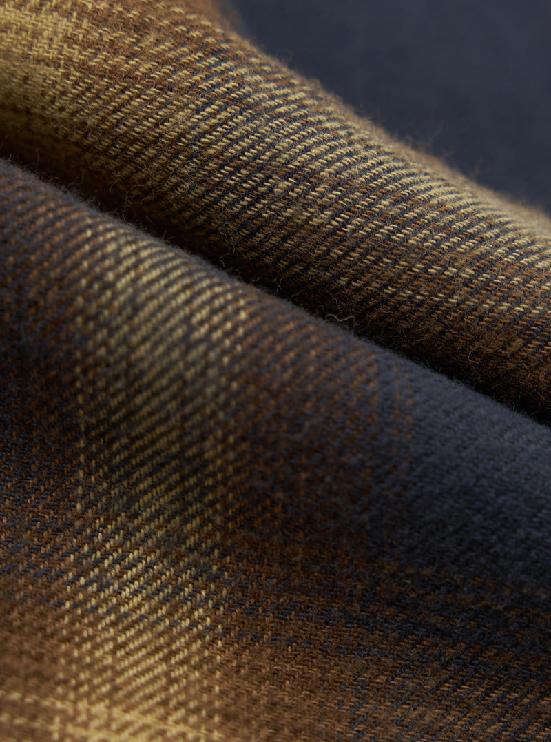 Close-up of the Navy Canyon Check Pyjama Pant fabric. The material is a soft, woven check pattern in navy, brown, and tan. The fabric is folded, showing the texture.