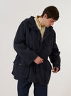 A model wears the Navy Seo Recycled Nylon Boston Parka, shown from the back against a plain white background. The parka features a large hood, a loose and elongated silhouette, and a straight hem. The smooth, dark navy recycled nylon fabric is prominent, and the model is shown from the head down to the mid-thigh, highlighting the garment's full length and rear construction.