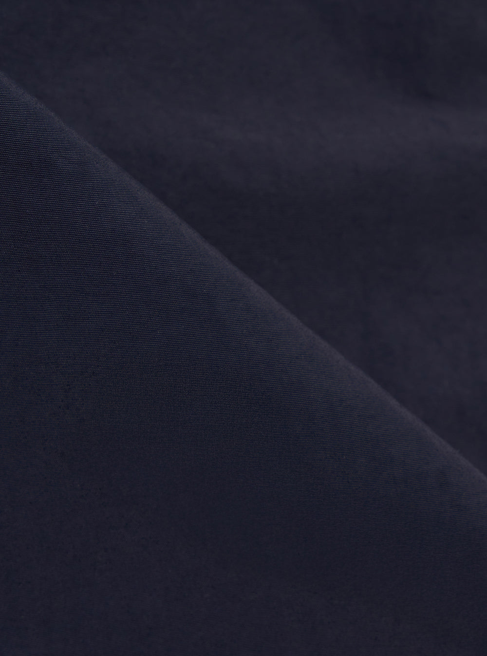 A close-up fabric swatch of the Navy Seo Recycled Nylon Boston Parka highlights the deep navy blue color and the lightweight, tightly woven texture of the recycled nylon material.
