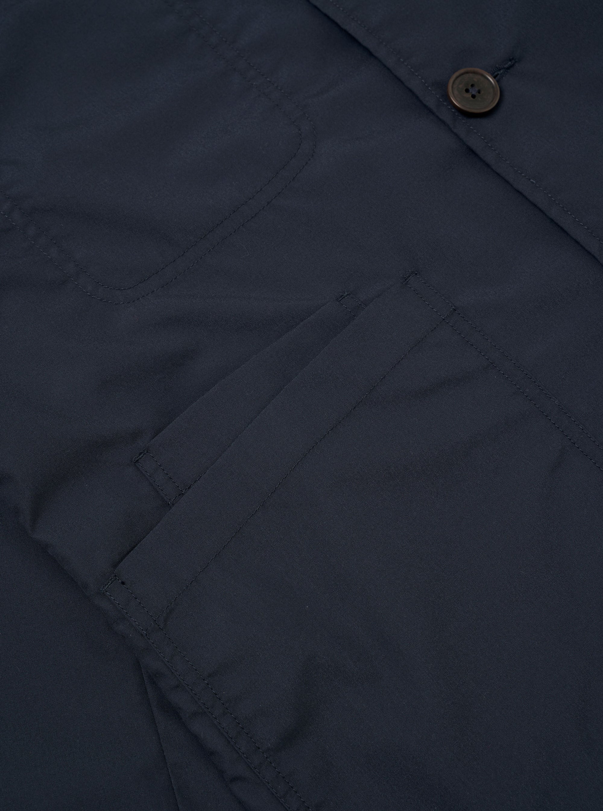 The Navy Recycled Polytech Bakers Jacket is displayed from the back as a flat lay against a white background. The image highlights the clean construction of the shoulders, the two-piece sleeve design, and the straight hem.
