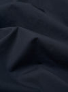 The Navy Recycled Polytech Bakers Jacket is displayed as a flat lay against a plain white background. The jacket features a classic collar, a five-button front closure, and multiple patch pockets, including one on the chest and two larger ones at the waist. The hem is slightly curved at the front.