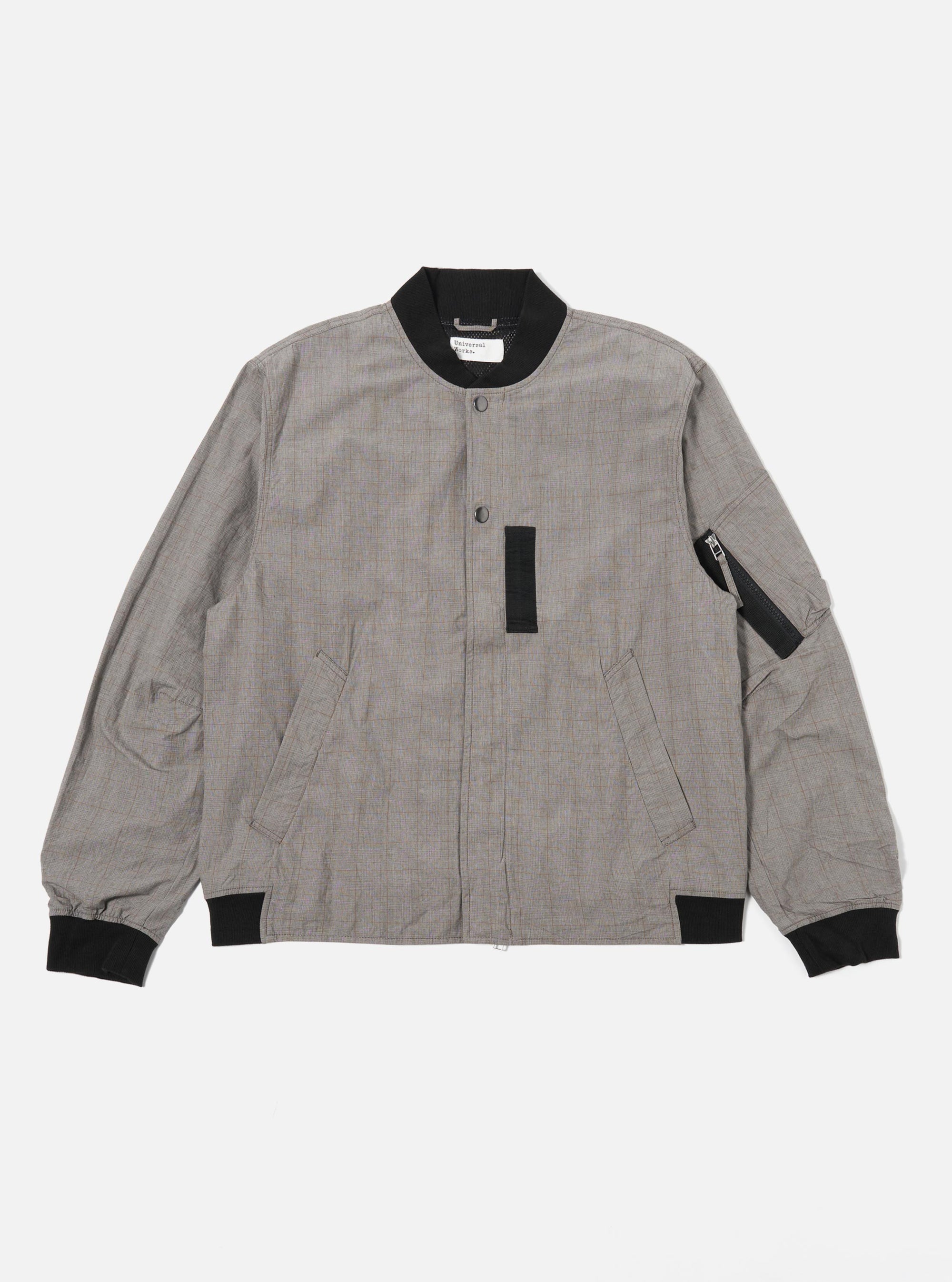 The Grey Brown Wales Glen Check NS Bomber Jacket is shown as a flat lay against a plain white background. The jacket features a prominent glen check pattern in shades of grey and brown, a full zip front, and a classic ribbed collar, cuffs, and hem. Two slanted welt pockets are visible on the front.
