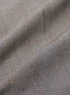 A close-up fabric swatch of the Grey Brown Wales Glen Check NS Bomber Jacket displays an intricate glen check pattern in shades of grey, light beige, and brown. The image highlights the detailed weave and color palette of the cotton fabric.