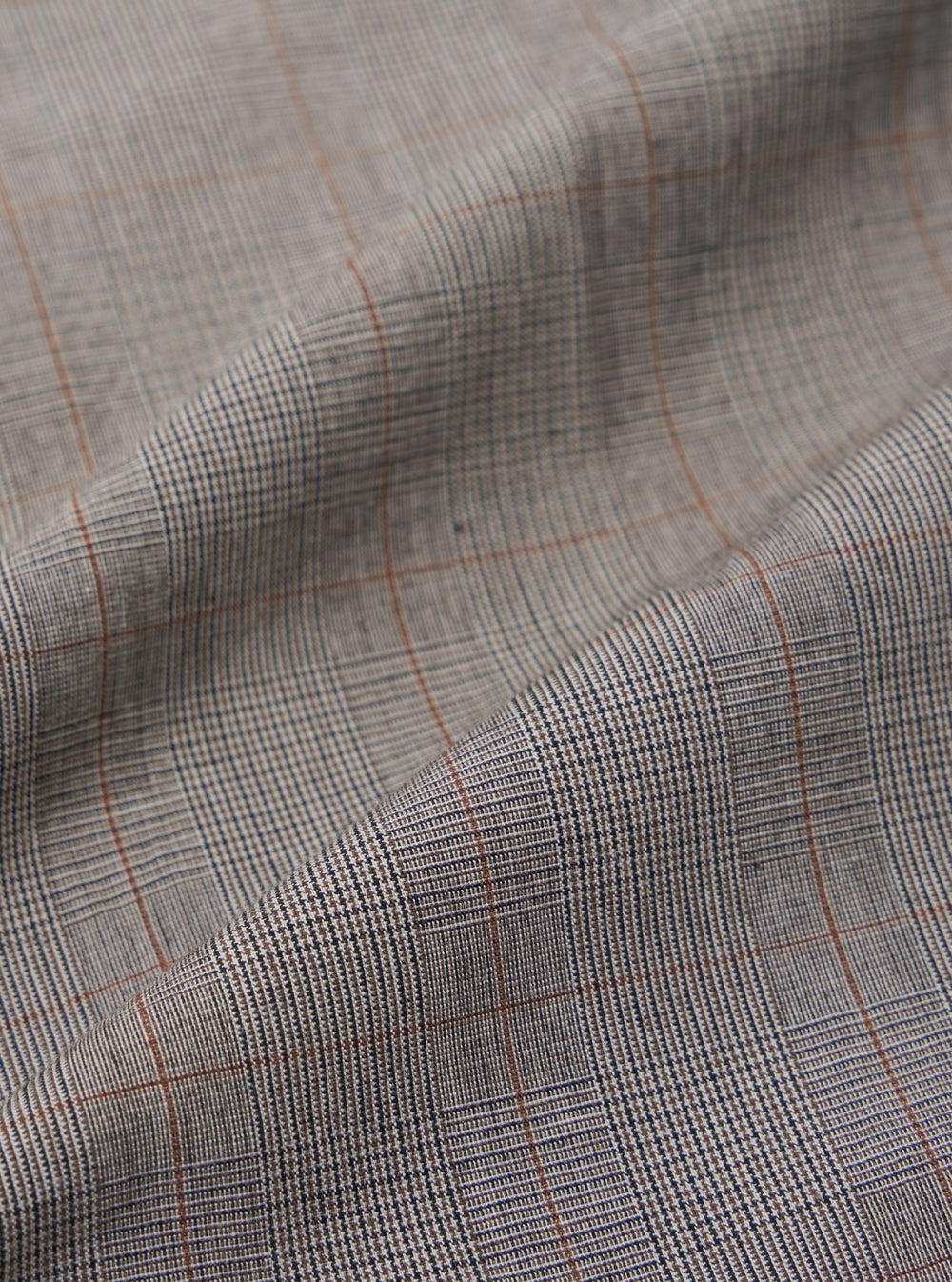 A close-up fabric swatch of the Grey Brown Wales Glen Check NS Bomber Jacket displays an intricate glen check pattern in shades of grey, light beige, and brown. The image highlights the detailed weave and color palette of the cotton fabric.